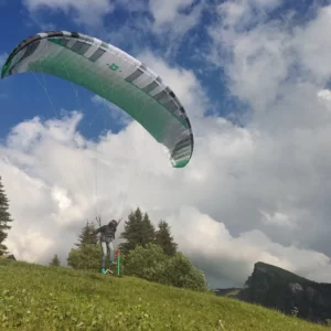 Green and white Nemo 5 paraglider canopy viewed from below against a partly cloudy sky